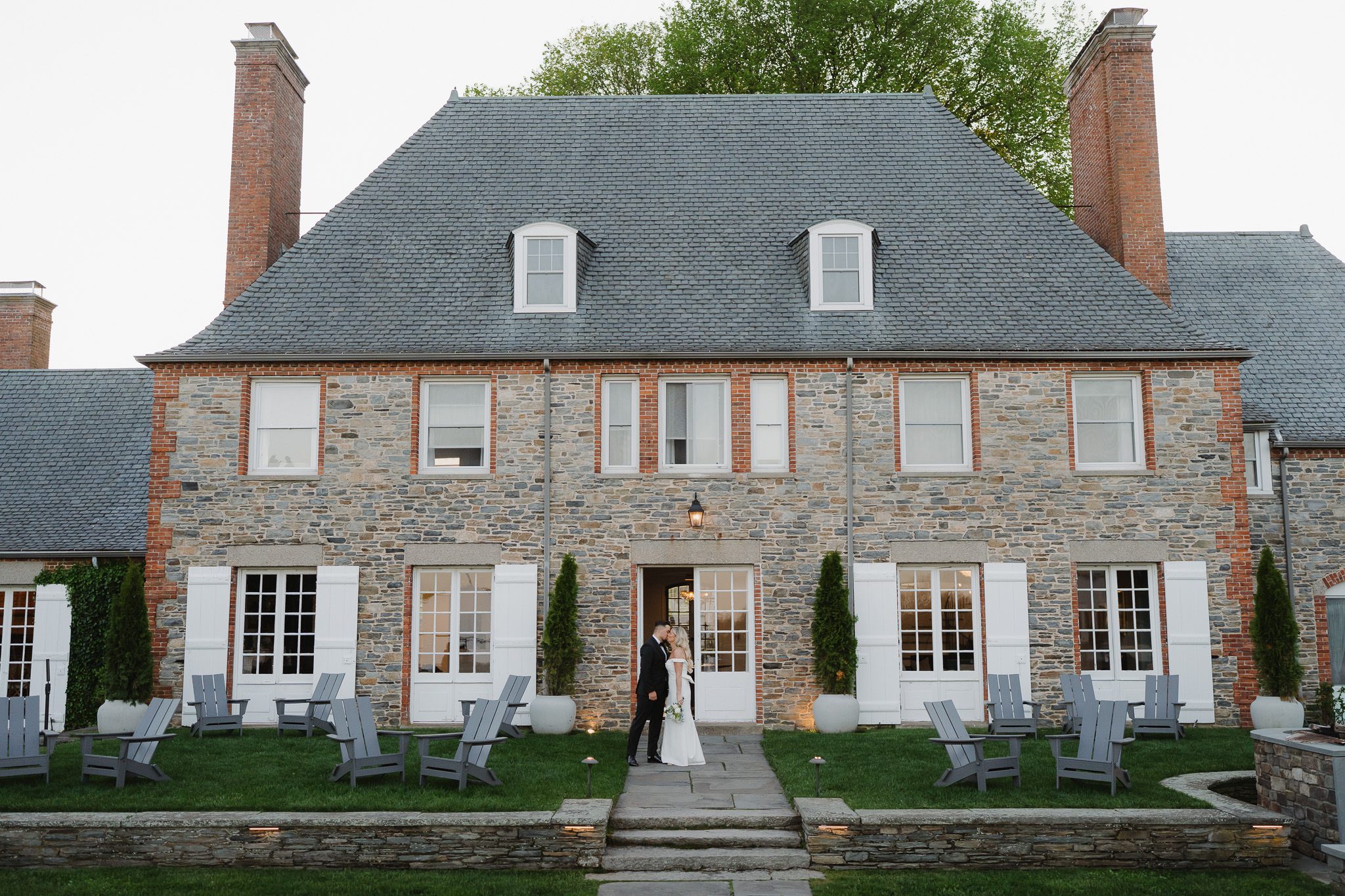 Bride and groom standing outside the historic brick estate building at Shepherd’s Run in South Kingstown