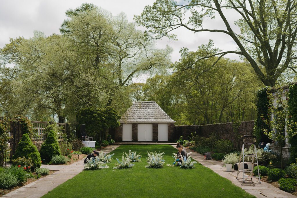 Wedding florist arranging ceremony flowers in the Beatrix Farrand Walled Garden at Shepherd’s Run in South Kingstown
